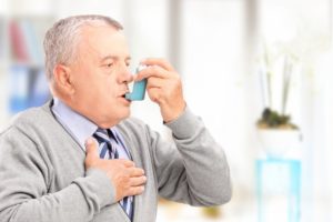 Мужчина применяет ингалятор от астмы