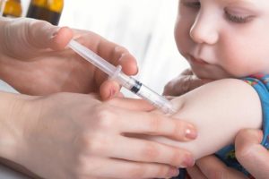 Ребенку ставят прививку в руку